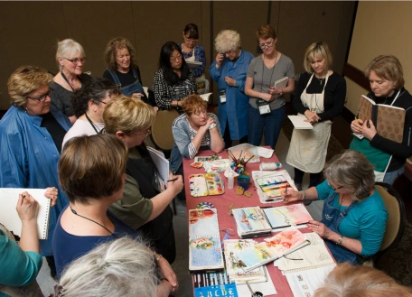 A group of people around a table, looking at several art pieces