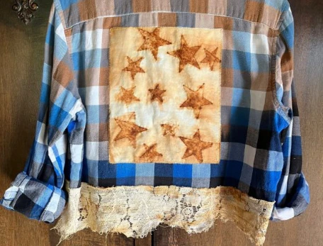 A blue checkered quilt with yellow stars in the middle and lace on the bottom edge